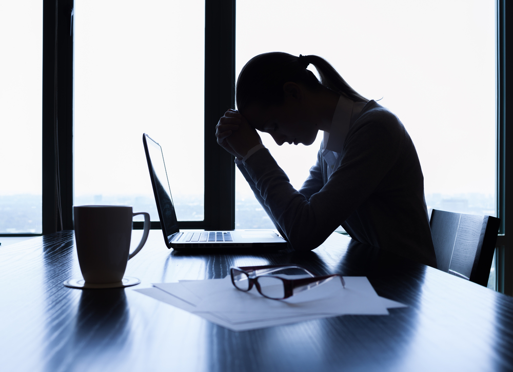 Stressed-looking woman sits in front of her laptop
